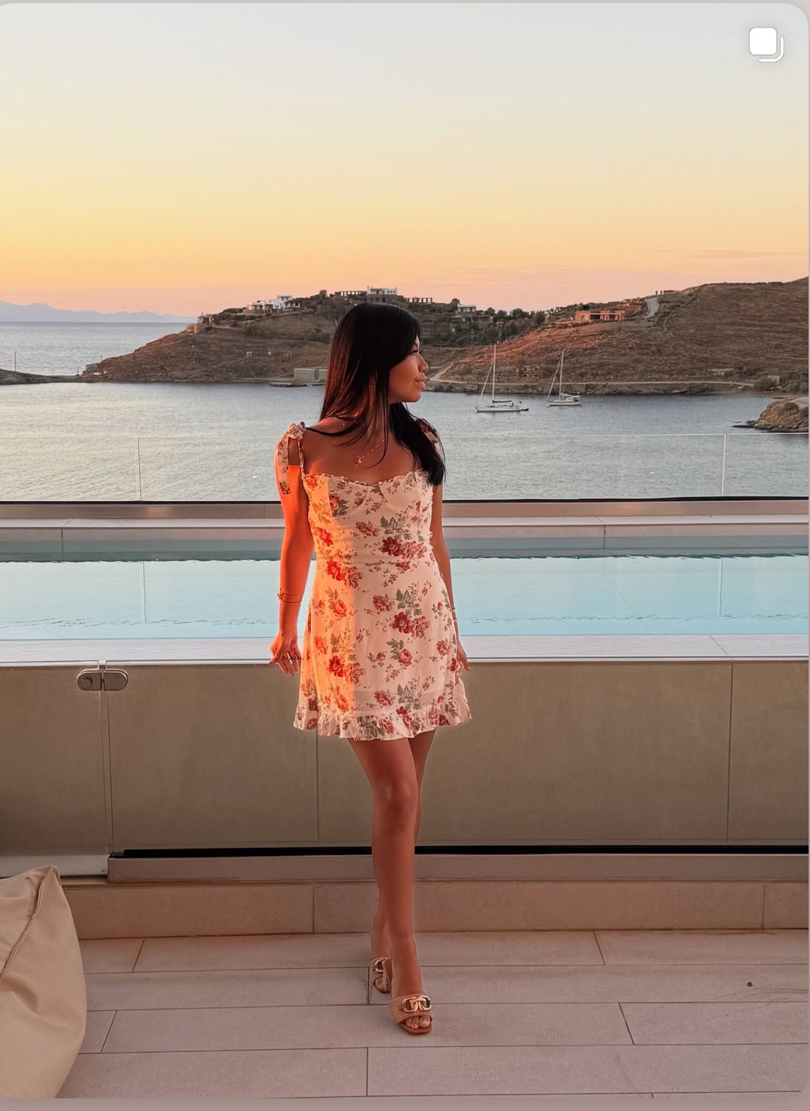 Leslee in a floral dress at golden hour overlooking a Greek bay