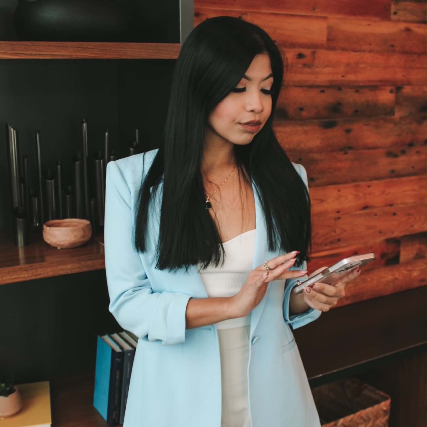 Leslee in a light blue blazer reviewing her phone